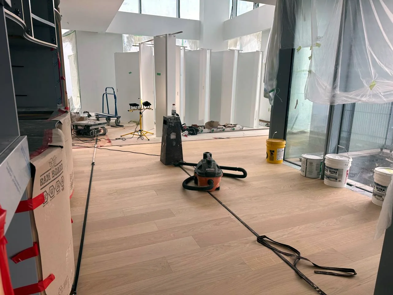 Flooring installation in progress with staged boards, floor protection, and tools on site